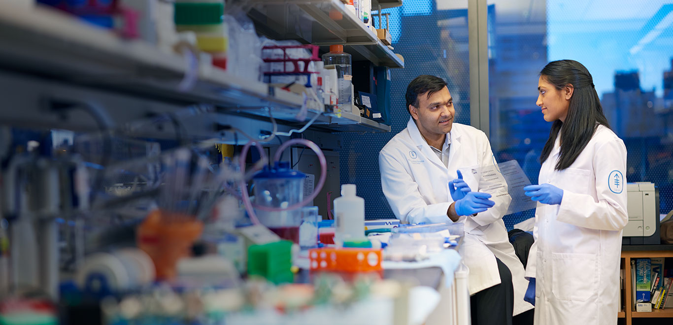 Two MSK Colleagues wearing lab coats having a discussion in a lab