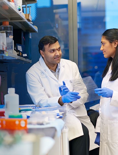 Two MSK Colleagues wearing lab coats having a discussion in a lab