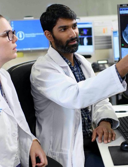 Two MSK Colleagues wearing lab coats looking at a computer monitor