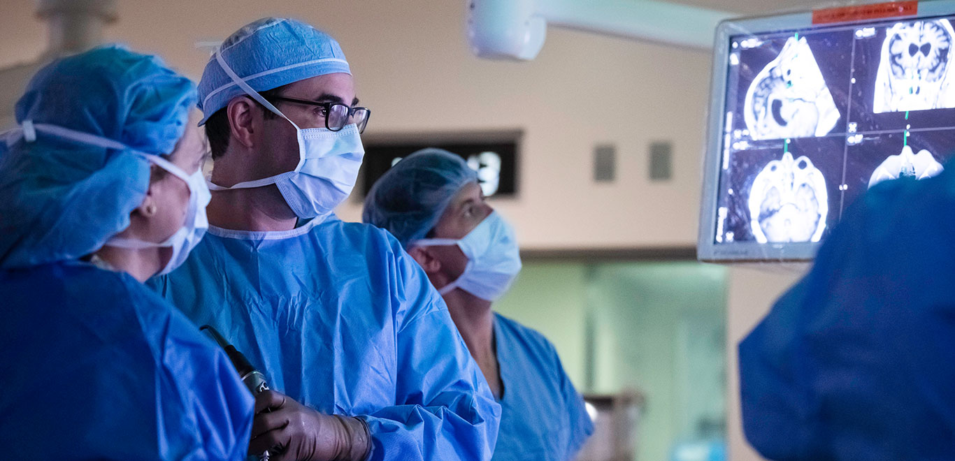 Three MSK Colleagues in operating theatre looking at X rays of brain