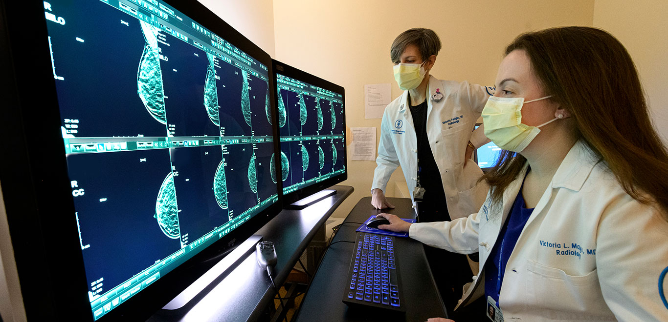 Two MSK colleagues in lab coats looking at mulitple computur screens with X ray information